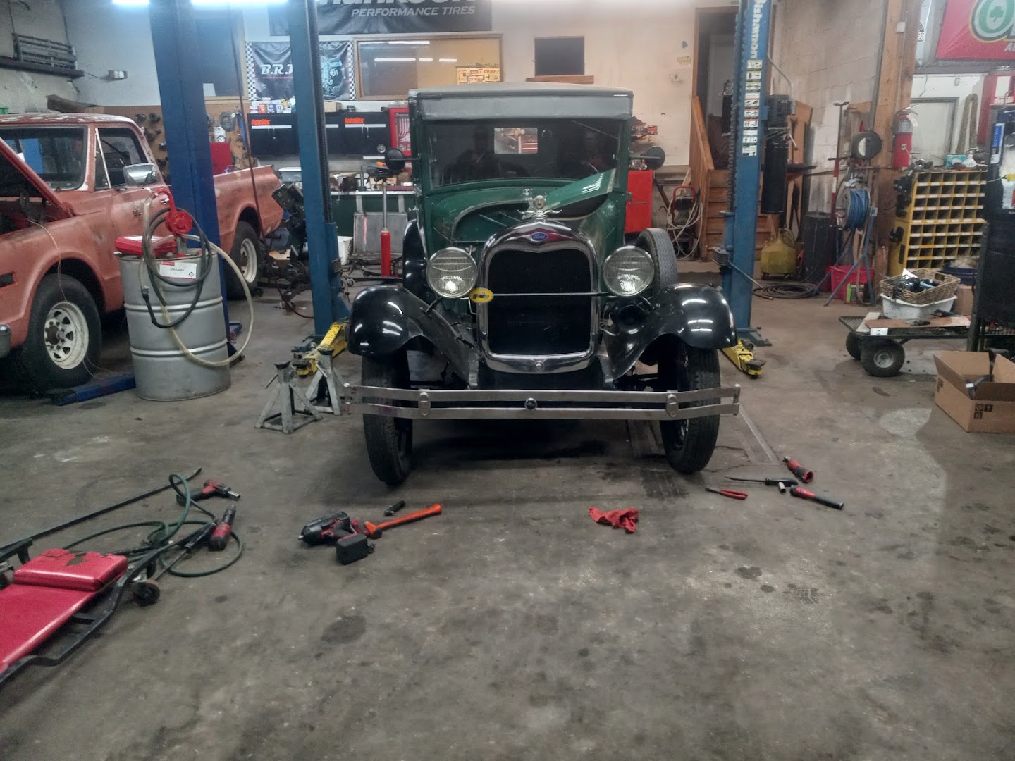 A Ford Model A truck between the two-post lifts in the shop