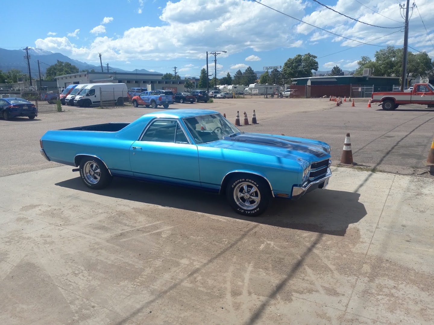 A bright blue El Camino SS in the shop lot with Pikes Peak in the distance