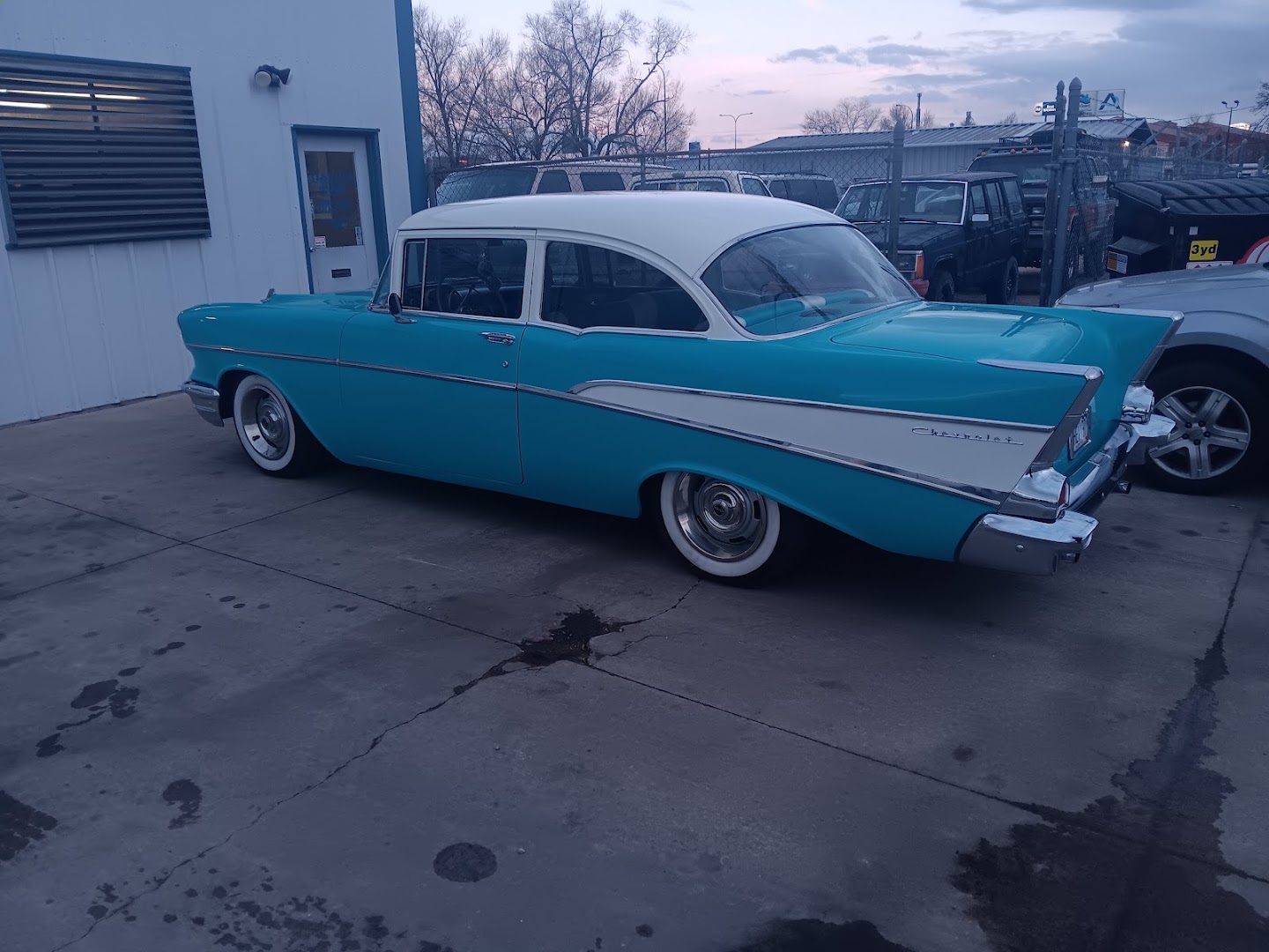 A custom white pickup truck with pinstriping outside the shop