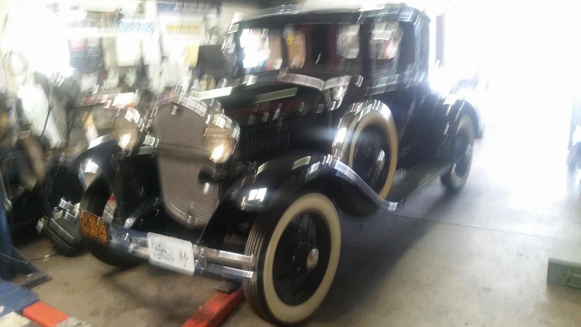 A restored Ford Model A coupe with red wire wheels and whitewall tires
